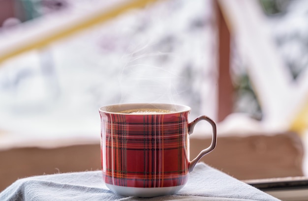 Foto café negro en una taza en el alféizar de la ventana iluminación natural un paisaje nevado de invierno en el fondo