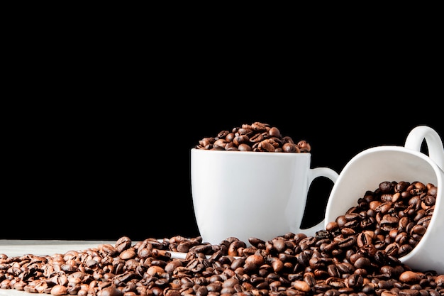 Café negro en taza blanca y granos de café sobre fondo negro. Vista superior, espacio para texto