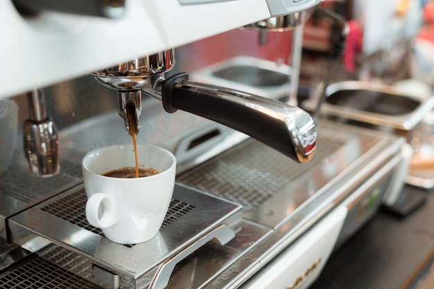 Café negro en taza blanca puesta en cafetera