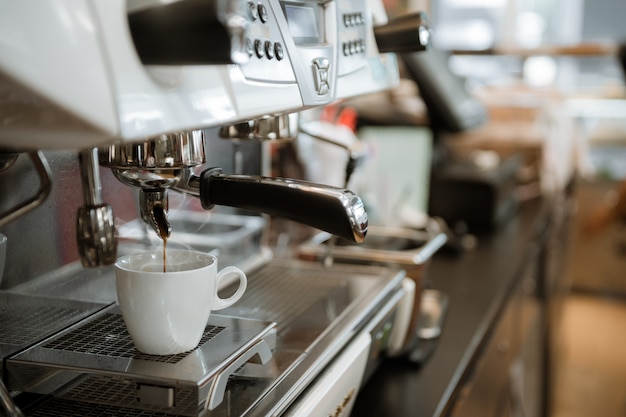 Café negro en taza blanca puesto en cafetera