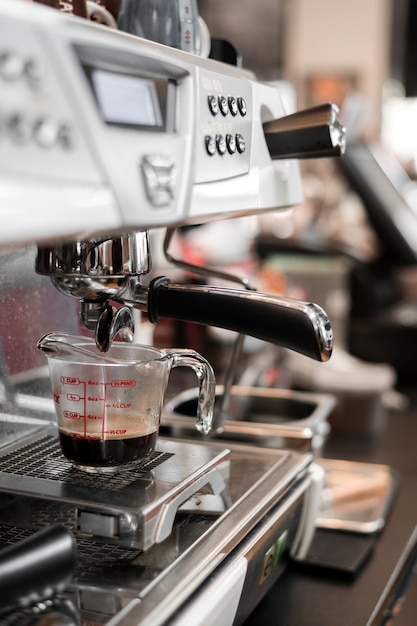 Café negro en taza medidora poner cafetera