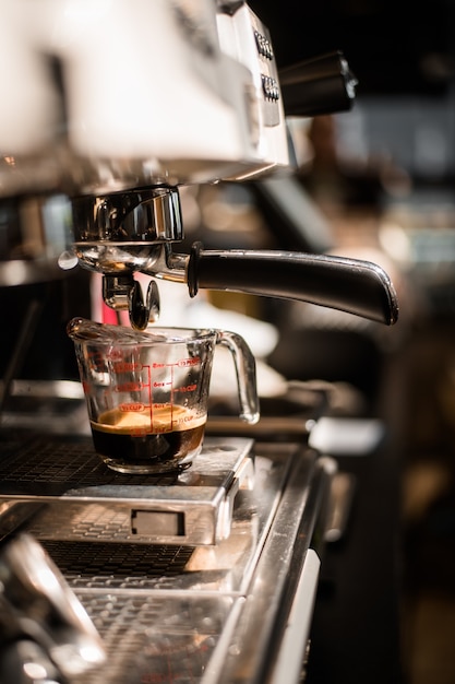 Café negro en taza medidora puesta en cafetera