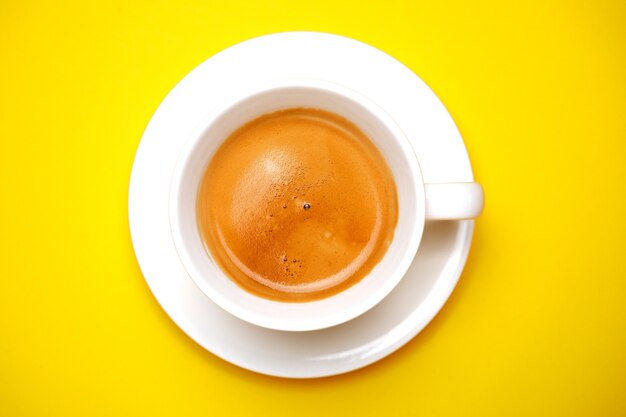 Café negro en una taza sobre un amarillo