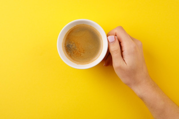 Café negro en una taza sobre un fondo amarillo