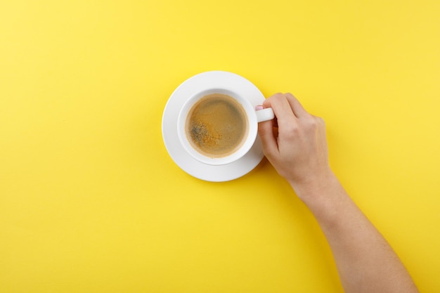 Café negro en una taza sobre un fondo amarillo