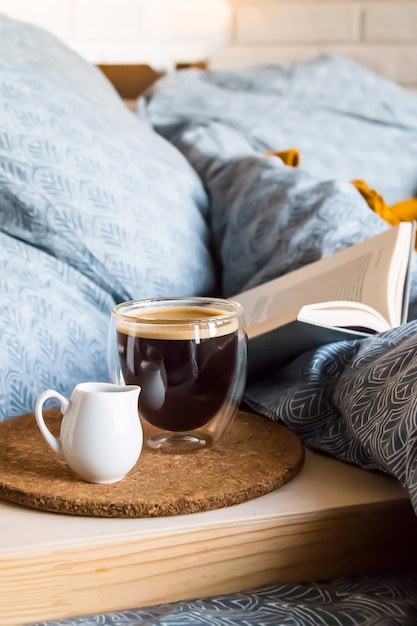 Café negro en una taza transparente en la cama en la mañana de otoño