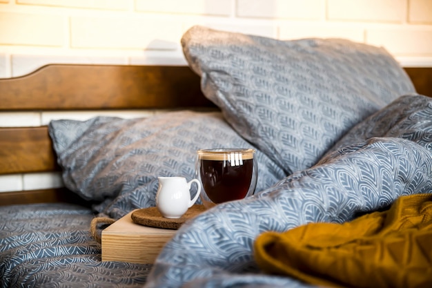 Café negro en una taza transparente en la cama en la mañana de otoño