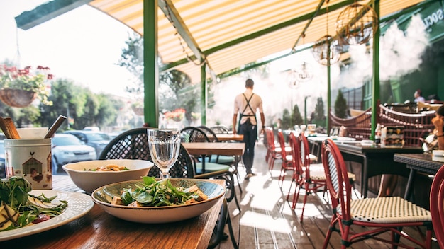 Café no terraço de verão com mesa servida e garçom