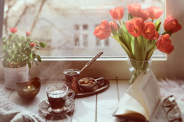 Café oriental cocinado en una cafetera de cobre tradicional turca con flores en el alféizar de la ventana