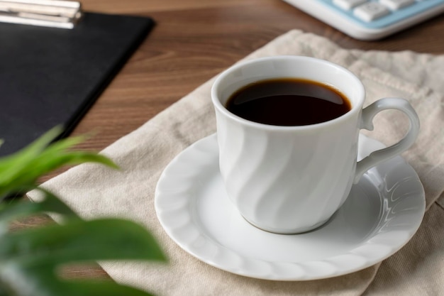 Café oscuro en una taza blanca sobre una mesa de maderaxDxA