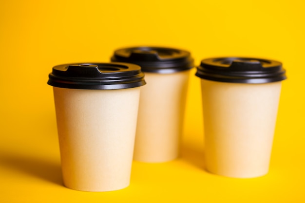 Café para viagem. copo de papel com café em um fundo amarelo.