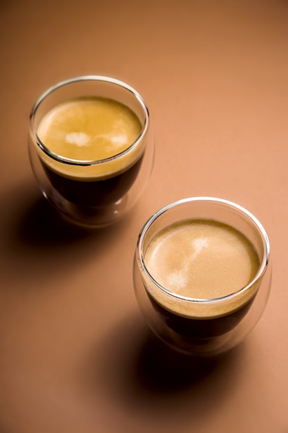 Café preto com espuma em copos modernos na planície