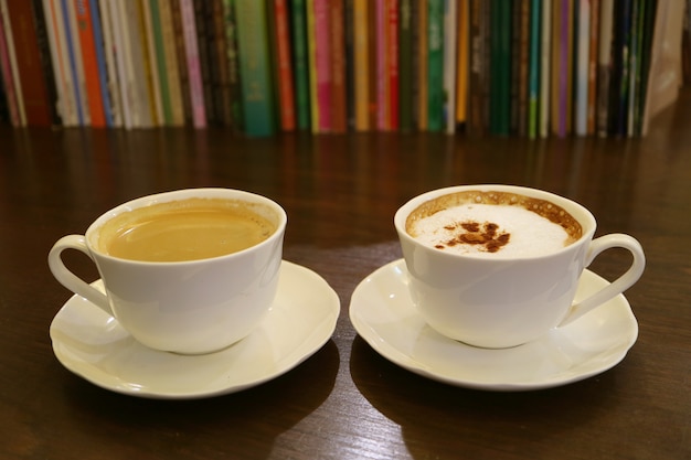 Café preto e café cappuccino com linhas embaçadas de livros no fundo