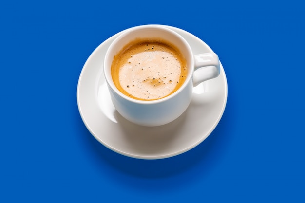 Café preto em um copo em uma superfície azul