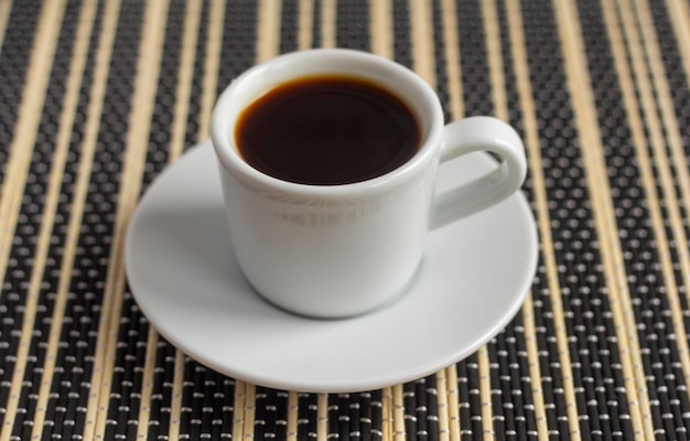 Café preto em uma pequena xícara de café em cima da mesa.