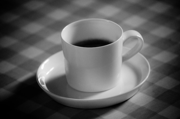 Foto café preto em xícara em toalha de mesa marcada