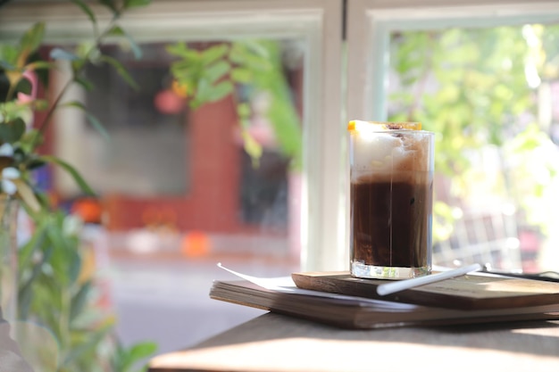 Café preto gelado com laranja em fundo de madeira