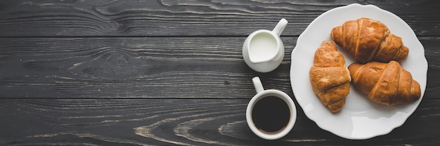 Foto café y productos lácteos cerca del plato con cruasanes