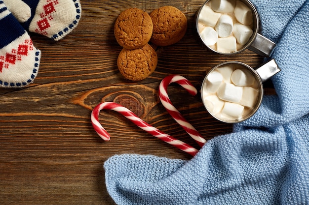 Café quente caneca de bebida de Natal com bengala de marshmallow vermelho doce no fundo de madeira ano novo