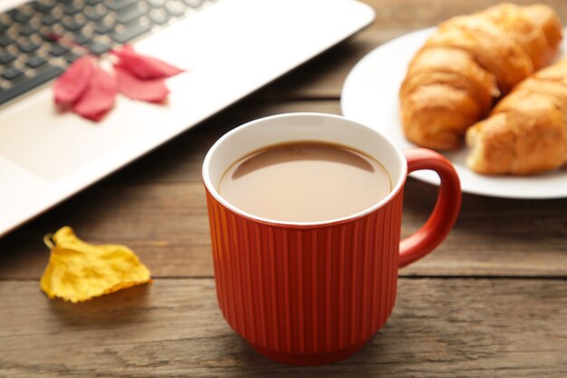 Café quente com croissant e folhas de outono em cinza - conceito de relaxamento sazonal.