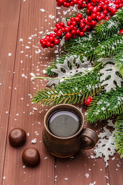 Café quente de Natal, abeto, folhas frescas, bombons de chocolate e neve artificial.