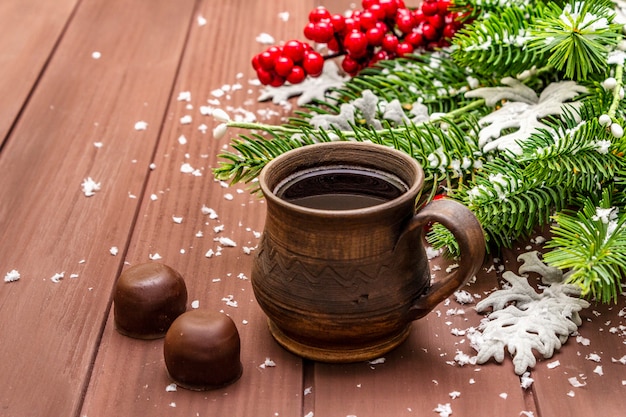 Café quente de Natal, abeto, folhas frescas, bombons de chocolate e neve artificial.