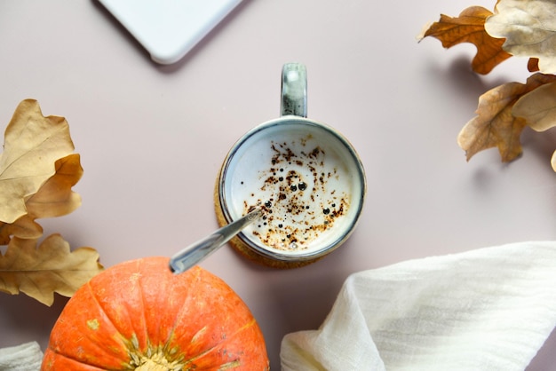 café quente de outono sobre fundo claro com folhas amarelas e abóbora