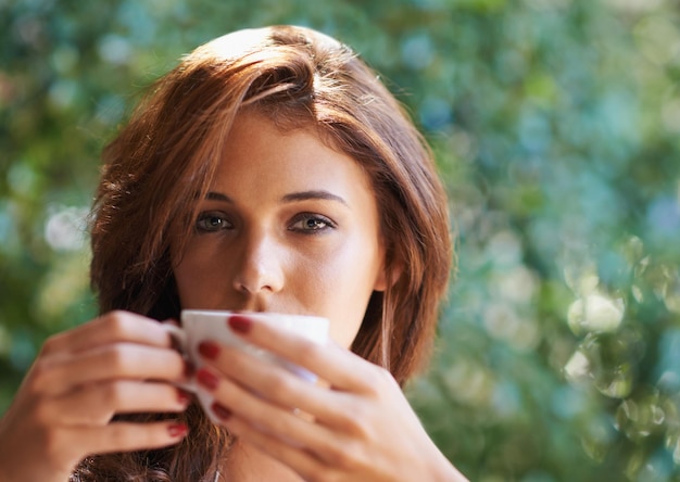 Café quente de verão Retrato de uma jovem atraente relaxando ao ar livre com uma xícara de café