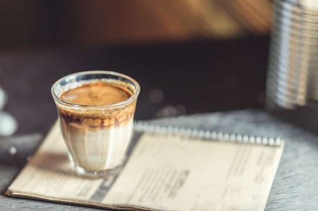 Café quente do latte no vidro na tabela de madeira na cafetaria.