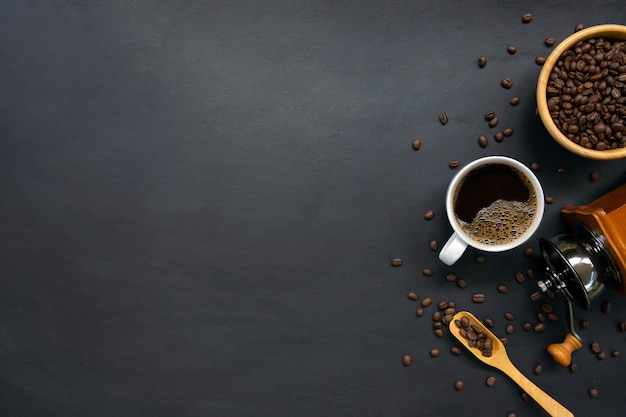 Café quente e feijão na mesa de madeira preta.