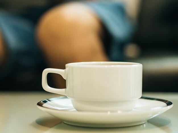 Foto café quente em copo branco servido na mesa em uma loja muito tranquila.