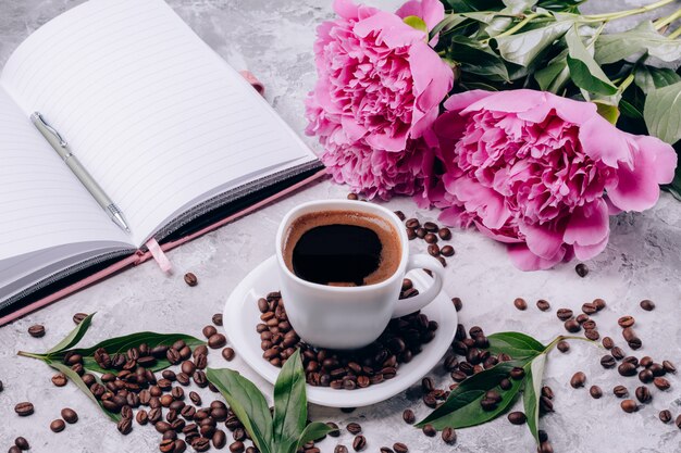 Café quente em uma tigela e peônias flores