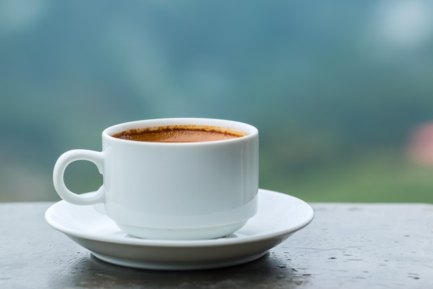 Café quente em uma xícara branca em cima da mesa.