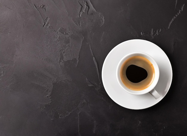 Café quente em uma xícara de café branca em fundo escuro com espaço de cópia