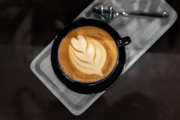 café quente latte art forma de coração na mesa preta