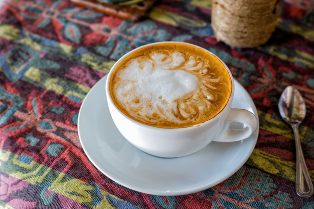 Café quente latte art na mesa de madeira