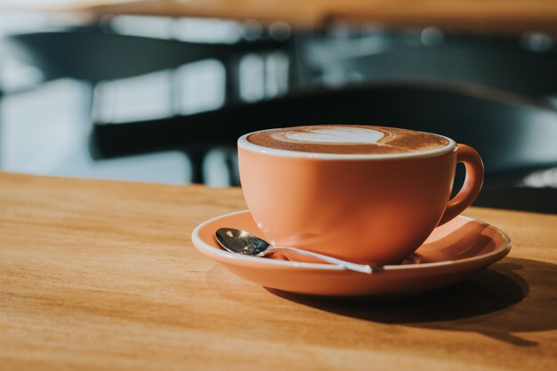 Café quente no copo no foco macio da tabela de madeira, efeito retro tonificado.