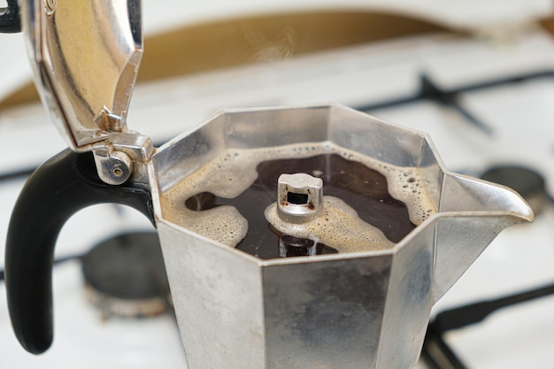 Café quente recém-preparado em uma cafeteira de gêiser em um fogão a gás
