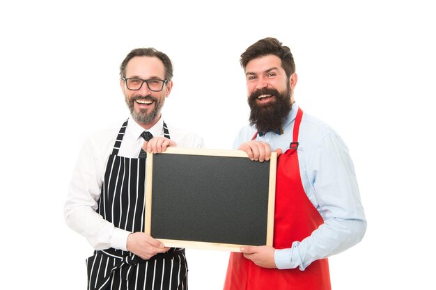 Café y restaurante de pizarra que abren hombres barbudos con espacio de copia de pizarra planificación del menú feliz equipo de chef en delantal negocio de catering bienvenido en pizarra los socios celebran la puesta en marcha