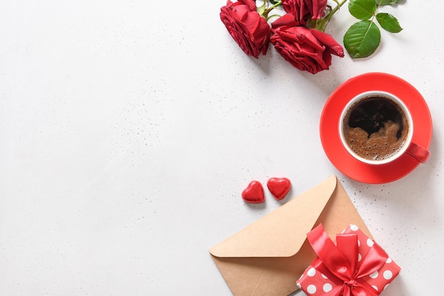 Café romántico del día de san valentín con carta de dulces de regalo y rosas rojas.