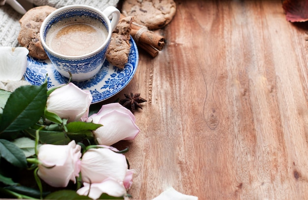 Café Romatic em uma xícara em um fundo de madeira com uma manta, um buquê de rosas brancas e aconchego de outono. bom Dia. vista superior. cópia spase