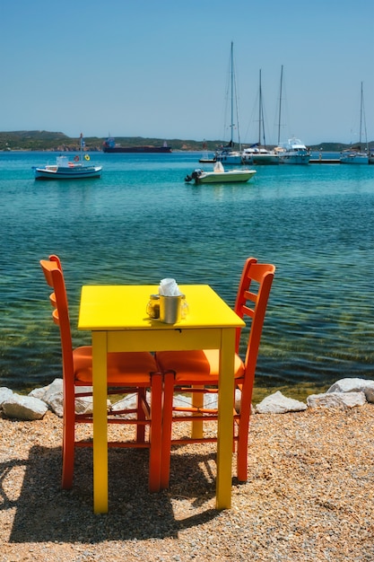 Cafe Tableon Strand in Adamantas Stadt auf der Insel Milos mit Ägäis mit Booten im Hintergrund
