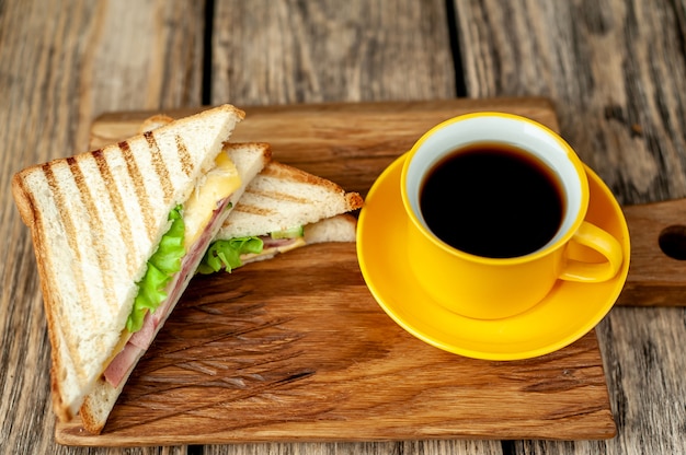 café en una taza amarilla y bocadillos en una tabla para cortar