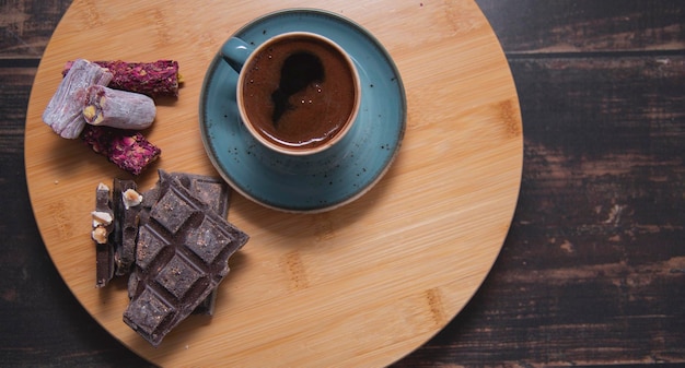 Café en taza azul sobre mesa de madera chocolate y dulce turco