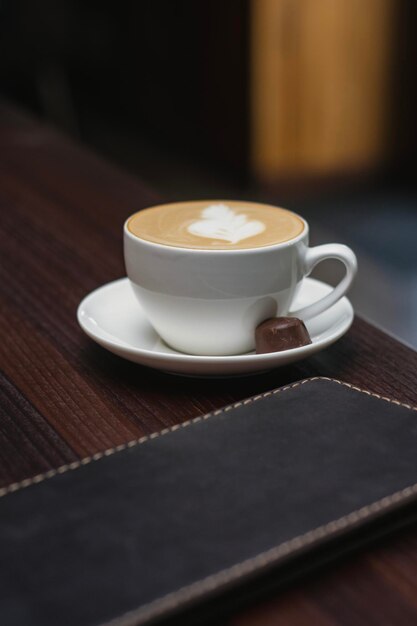 Foto café en una taza blanca con dulces en una mesa de madera en un restaurante