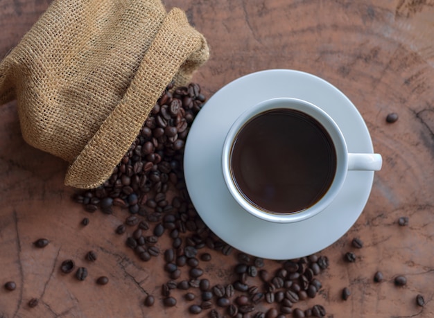 Café en una taza blanca y granos de café en una mesa de madera