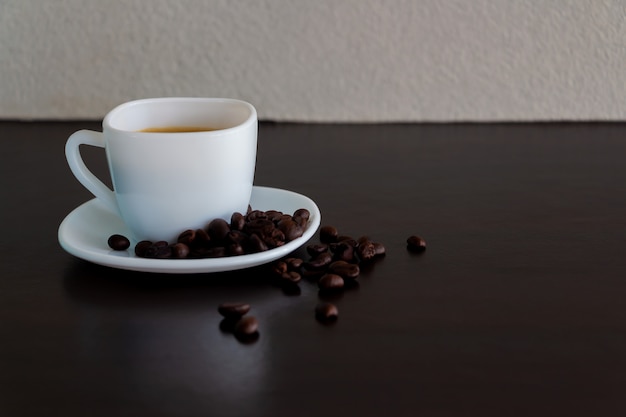 Café en una taza blanca y granos de café sobre la mesa