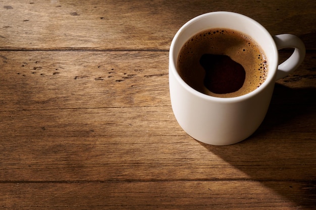 Café en una taza blanca sobre un fondo de madera