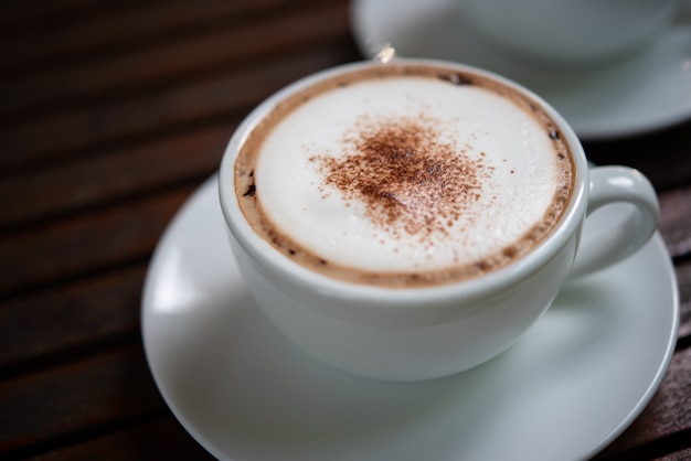 Café en taza blanca sobre la mesa en la cafetería.