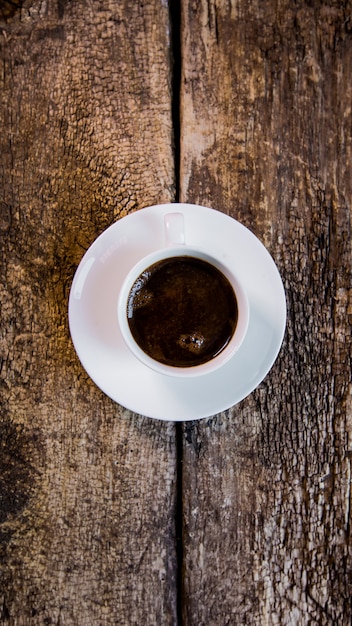 Café. Una taza de café caliente y granos de café tostados en una mesa de madera.